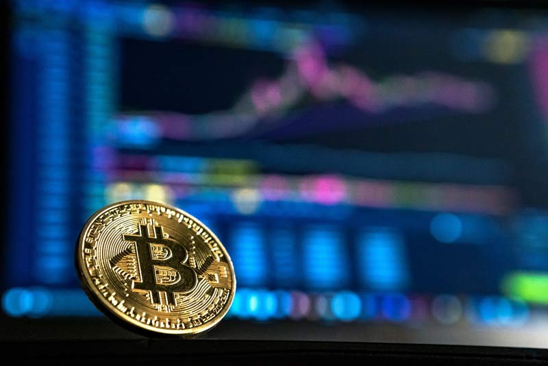 Bitcoin vor Bildschirm mit Bitcoinkurs